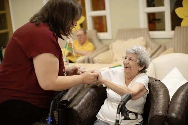 A carer helping an older woman walk with a mobility frame