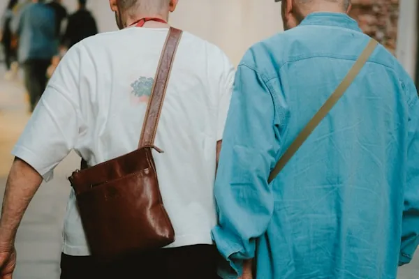 Two older friends walking together outdoors, holding hands