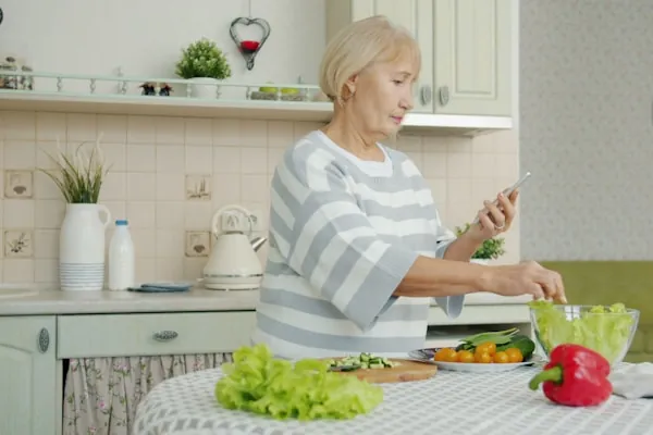 An older woman preparing a fresh salad in her kitchen
